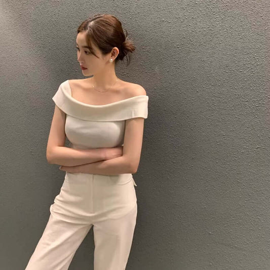 Elegant off-shoulder top with a wide collar, paired with stylish white pants, showcasing a chic and modern look.