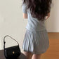Chic, youthful gray pleated dress paired with a stylish black handbag, showcasing a trendy back view.
